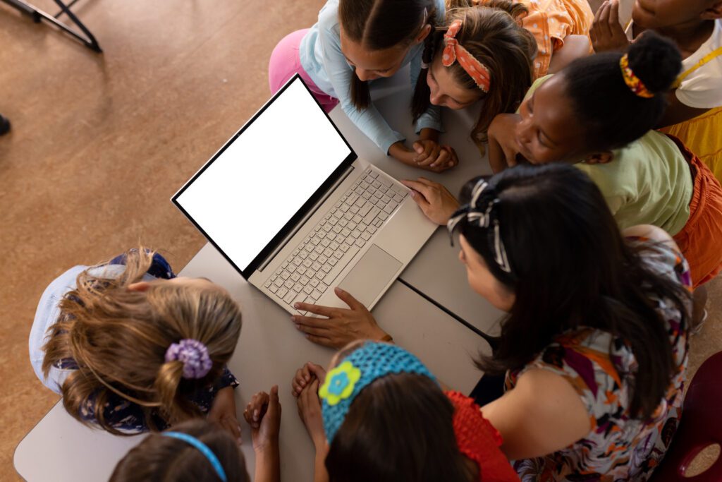 Teacher showing the kids something on the laptop at school