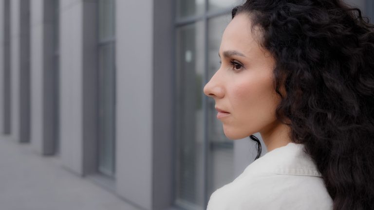 Close up back view Caucasian pensive thoughtful brunette lady with long curly hair looking away thinking dreaming pondering think waiting standing outdoors in city calm Latina Hispanic woman outside Close up back view Caucasian pensive thoughtful brunette lady with long curly hair looking away thinking dreaming pondering think waiting standing outdoors in city calm Latina Hispanic woman outside. High quality 4k footage